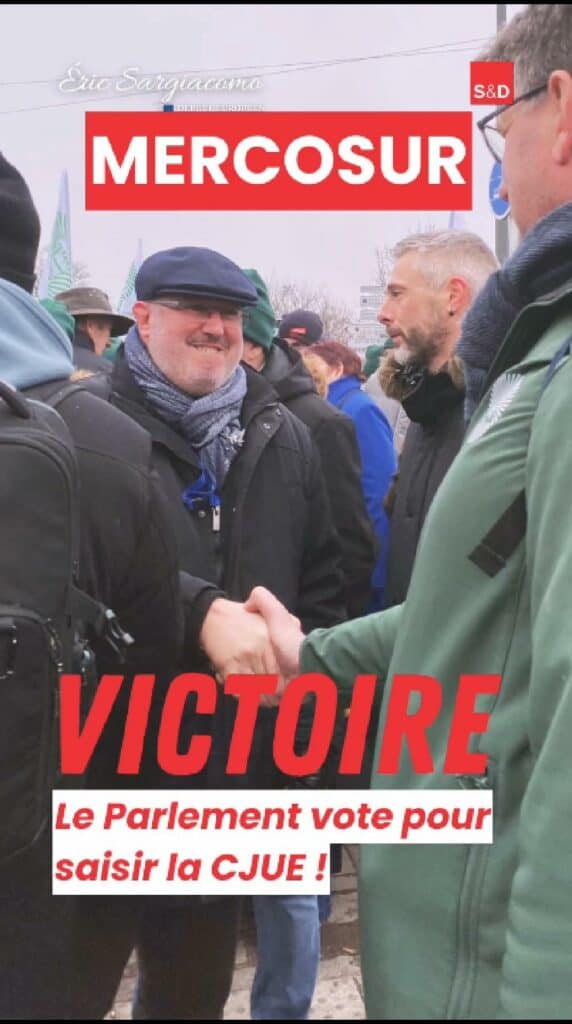 Député européen Eric Sargiacomo saluant lors d'une manifestation en faveur de la CJUE, entouré de participants, en tenue hivernale, sous ciel gris, lors d'une action pour la justice européenne.
