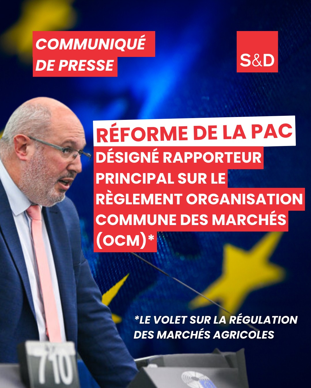 Député européen Eric Sargiacomo lors d'une conférence de presse sur la réforme de la PAC, portant une veste bleue et lunettes, avec un fond illustrant l'Union européenne.